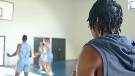 drinking water, female basketball player watching teammates practice on court, copy space