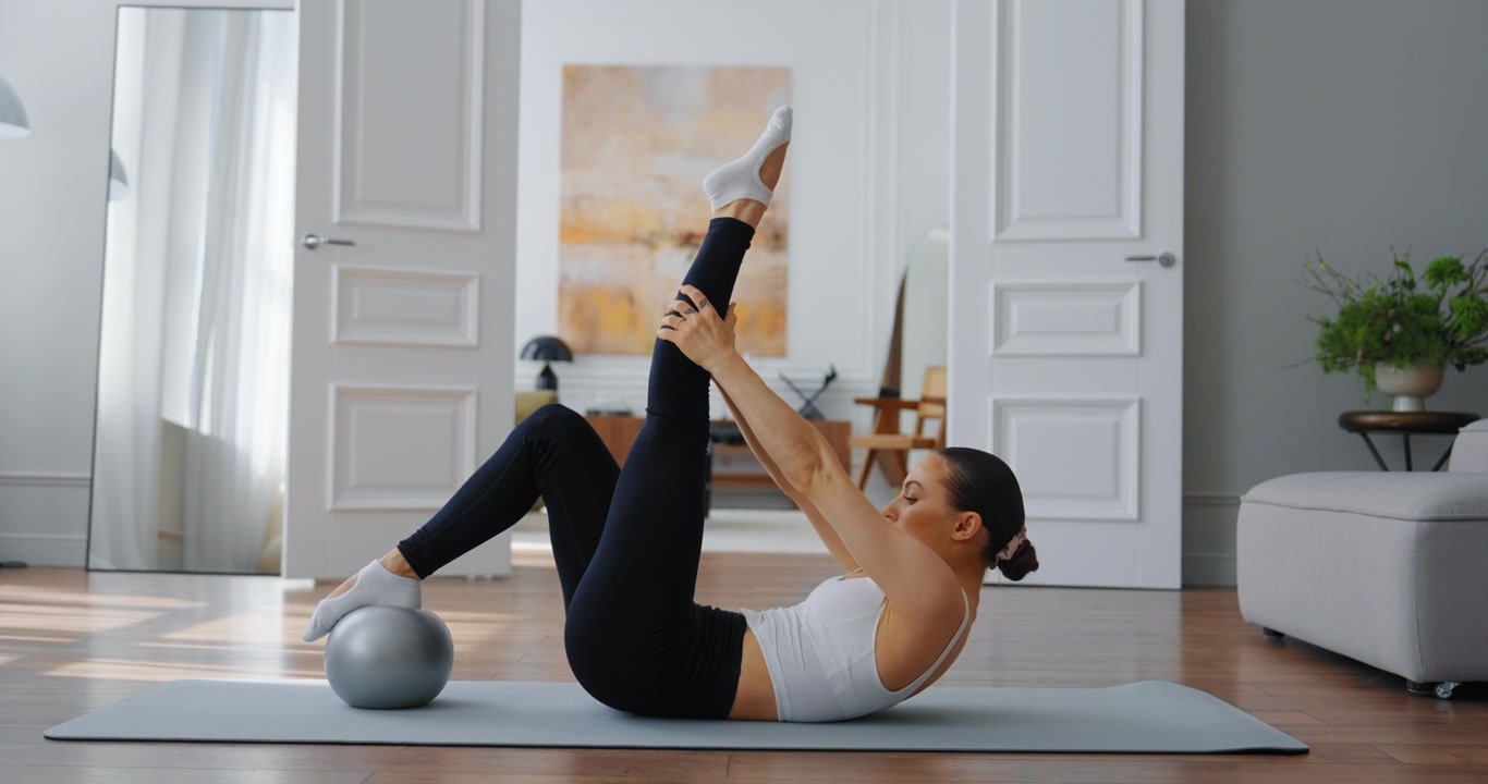 Woman Doing Pilates Core Exercises with Small Ball at Home