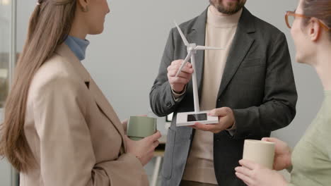 businessman explaining wind turbine model to two women in the office