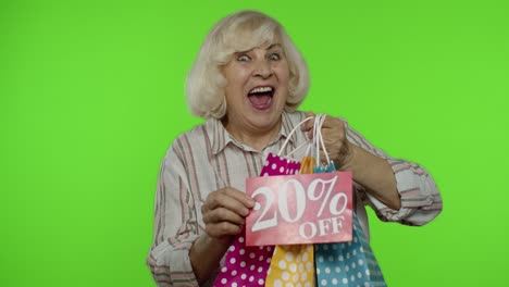 abuela mostrando el 20 por ciento de descuento en el letrero de inscripción y bolsas de compras. compras el viernes negro