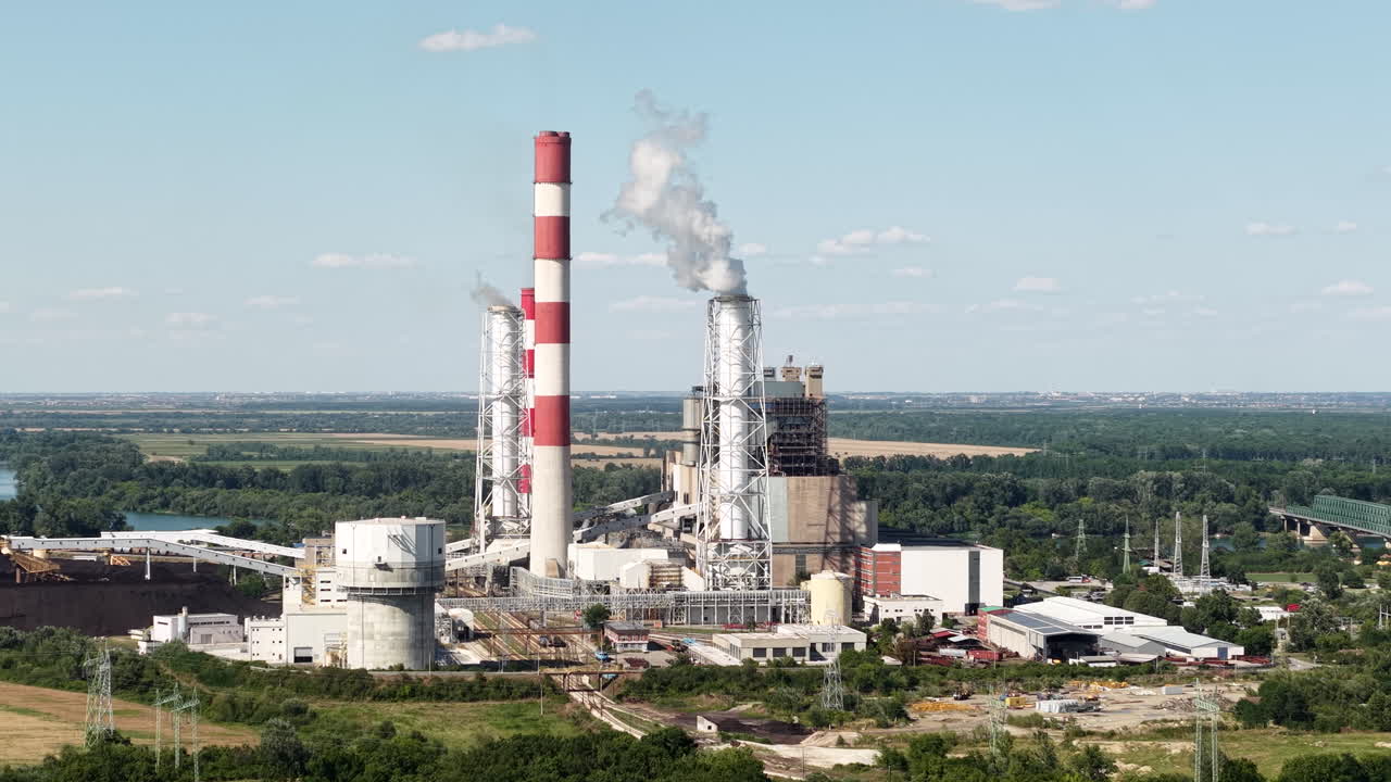 Aerial view of a power plant with chimneys releasing smoke