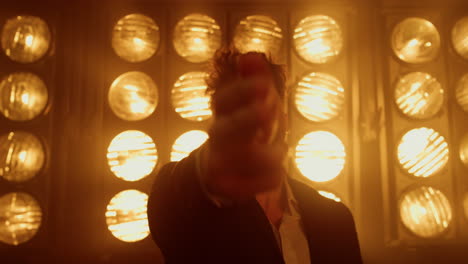 attractive man showing shooting gesture by hand standing club stage close up.