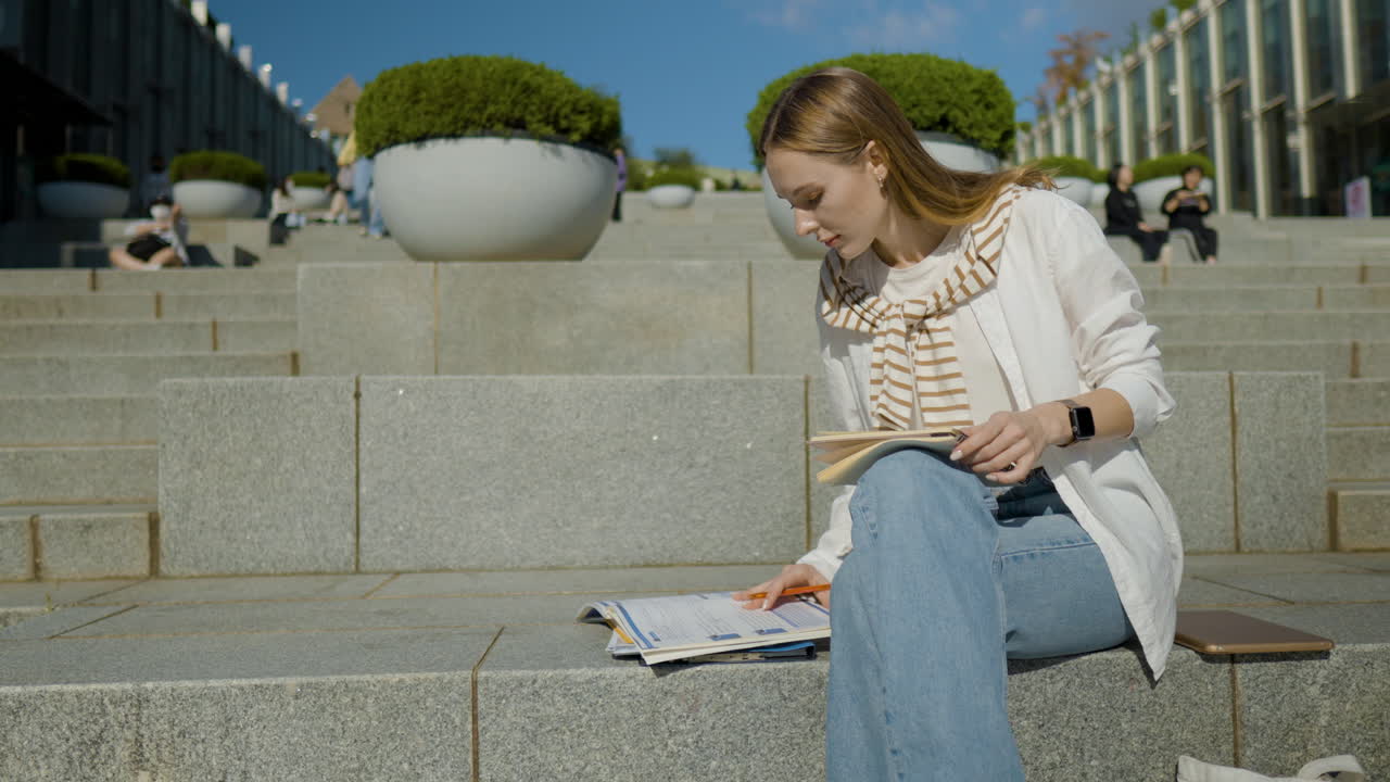 Beautiful Female College Student Sitting On Stairs Outdoor, Writing Notes On A Notebook In University Campus