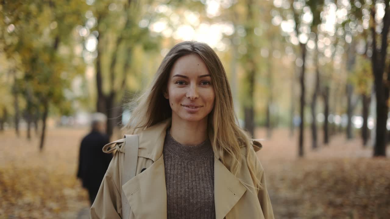 Front view of a cheerful woman walking by autumn park