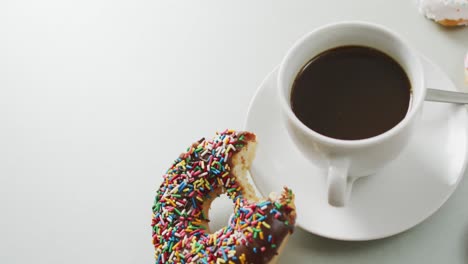 Video-of-donuts-with-icing-and-cup-of-coffee-on-white-background