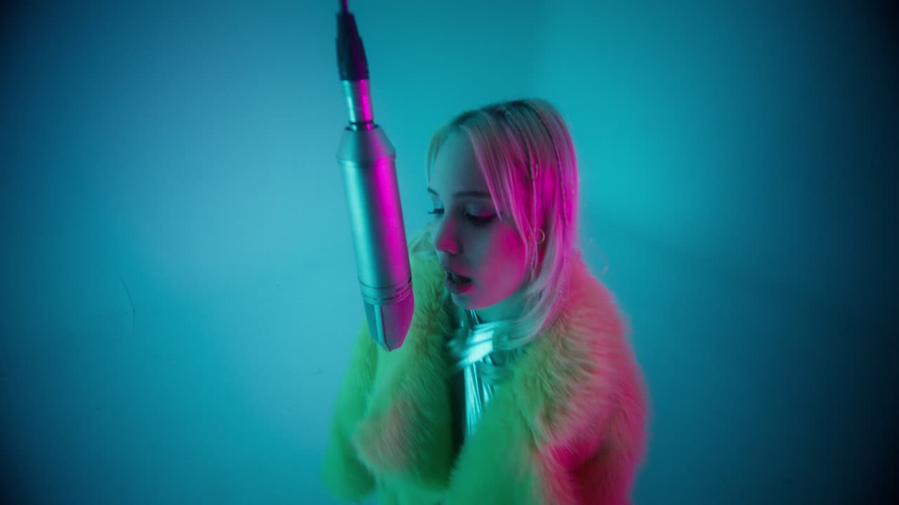 Woman Singing into Microphone in Neon Studio