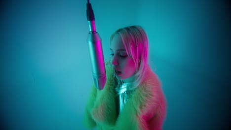 woman singing into microphone in neon studio