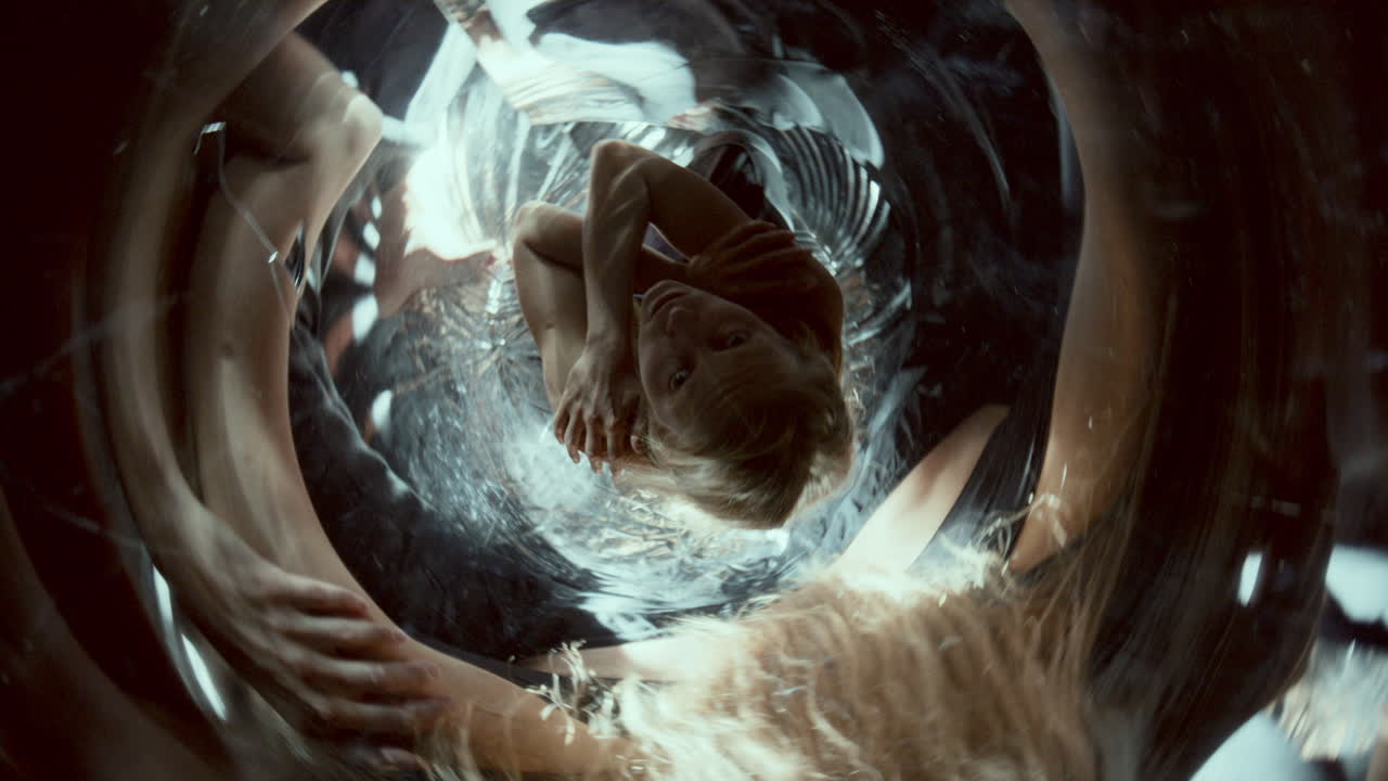Woman Sitting in Mirrored Space with Swirling Reflections and Flickering Light