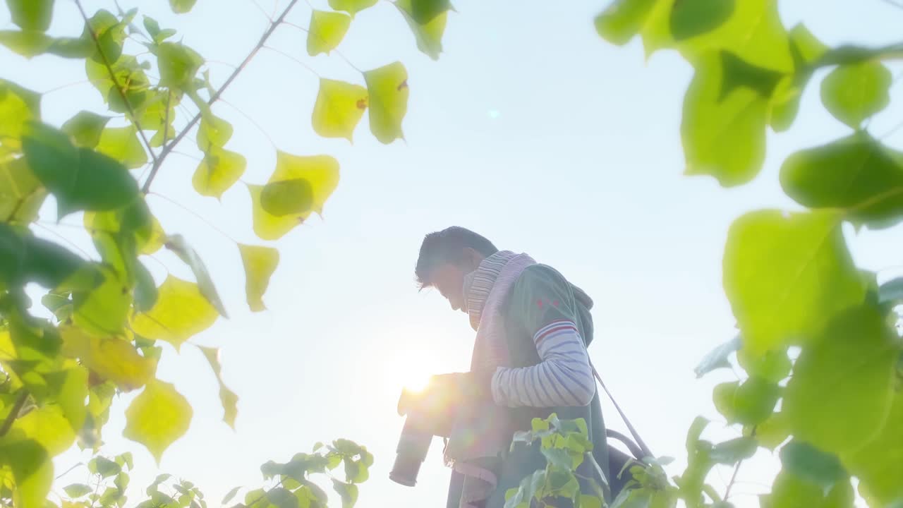 dslr 카메라를 얼굴에 가까이 대고 잎사귀를 통해 본 사진작가