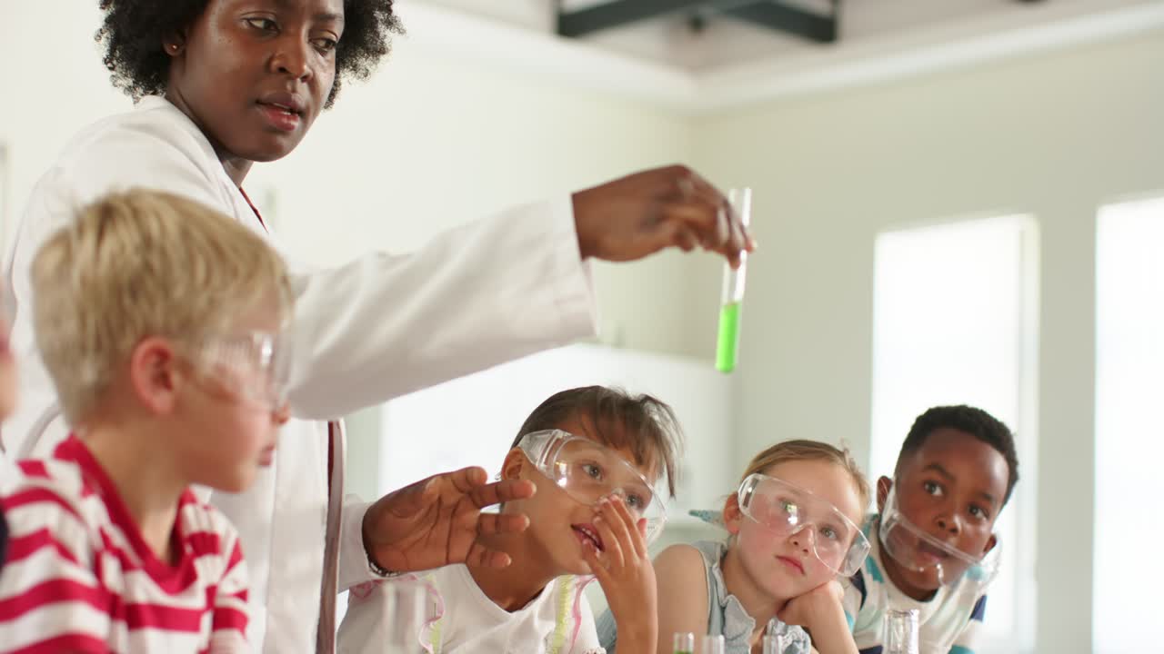 African American woman teacher in lab coat holding tube of green liquid teaching kids at lab