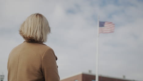 a woman looks at the american flag at the administrative building