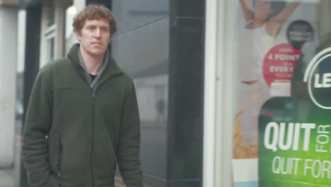 man walking in street past shopfront coronavirus sign