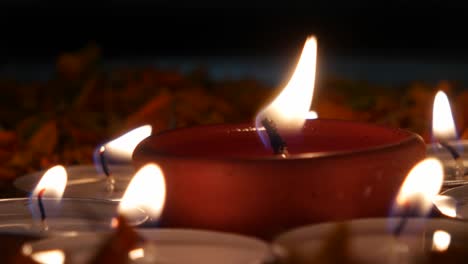 diyas or indian earthen lamp in a silver plate with marigold petals, lit up for diwali 'festival of light',surrounded by lit tea-light candles