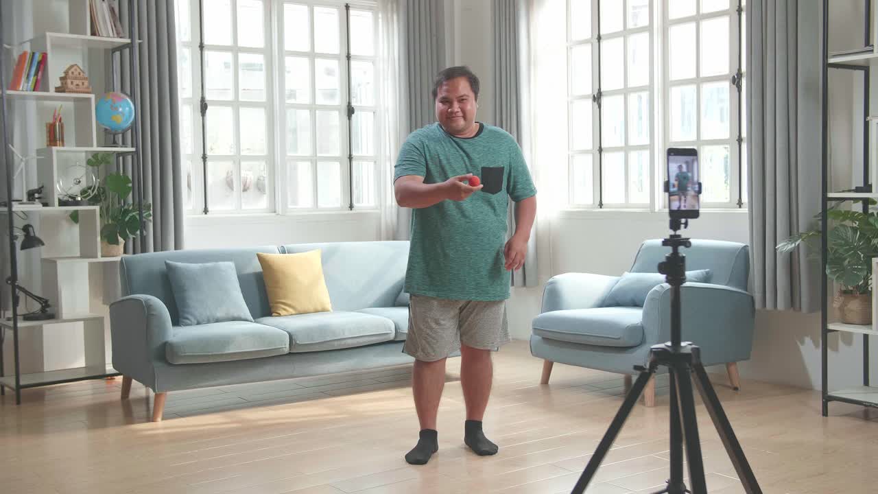 Asian Man Blogger Shoots Video Content For Social Networks By Smartphone Camera, Magician With Red Ball