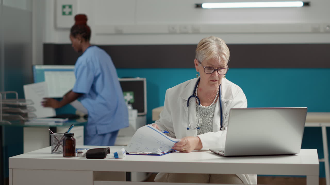 General practitioner working with appointment report on laptop