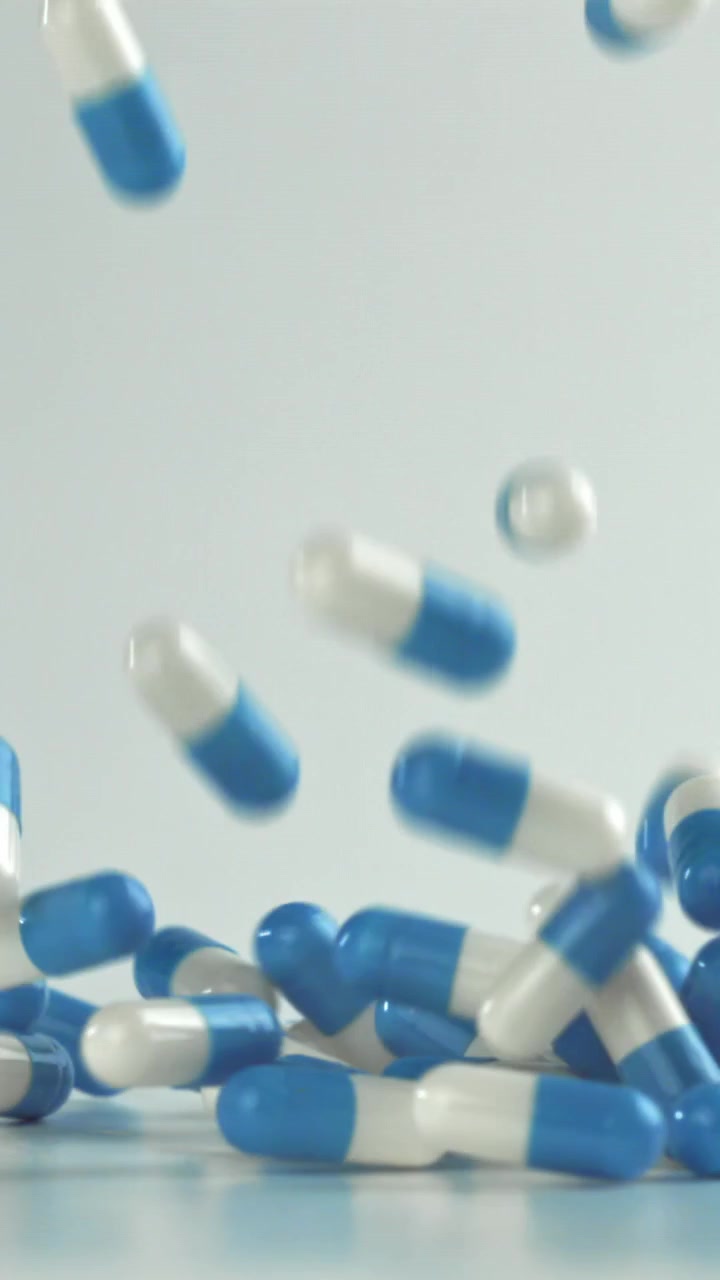 Capsule blu e bianche che cadono al rallentatore