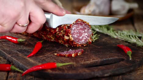 manos masculinas cortando el salami con un cuchillo.