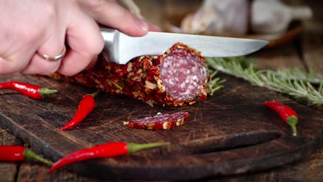 male hands slicing the salami with a knife.