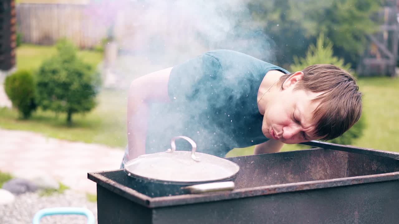 큐 느린 동작 젊은이가 열린 불 위에 그릴에 cauldron에서 pilaf를 만든다