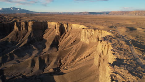 Drone-Shot-of-White-RV-Vehicle-on-Plateau-by-Road-in-Desert-Landscape-of-Utah-at-Sunset