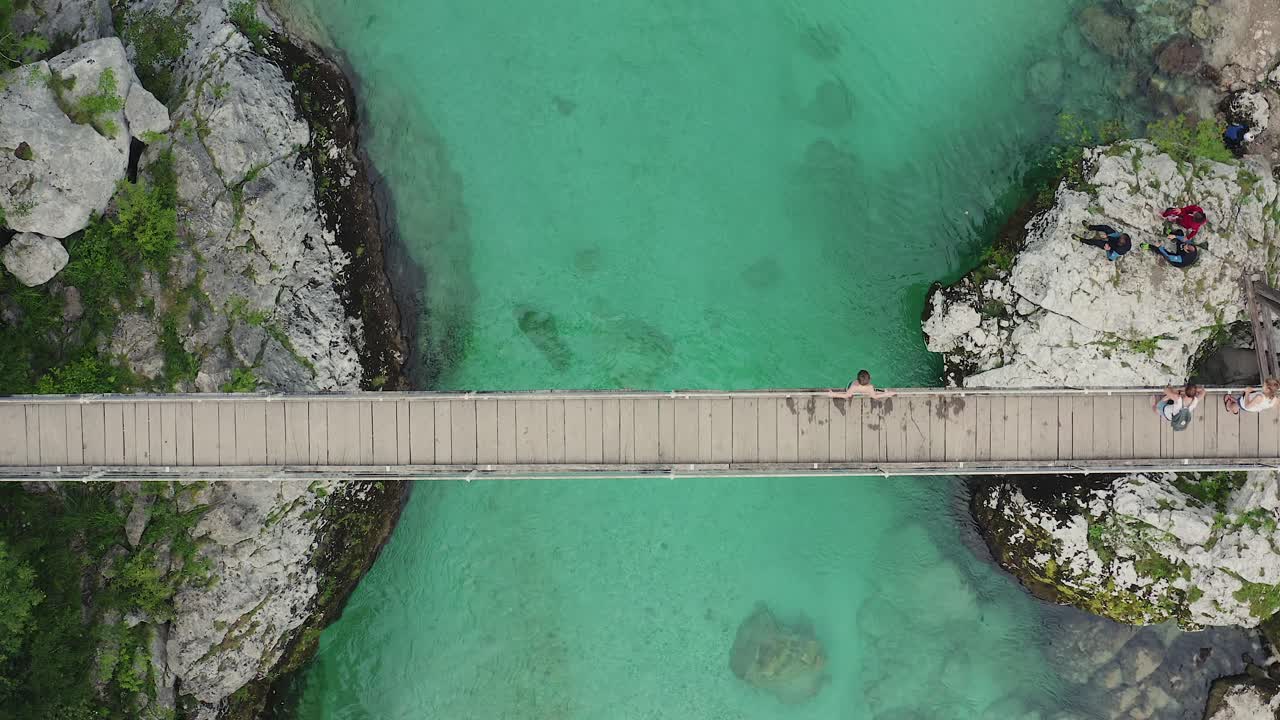 나무 다리에서 15미터 떨어진 10대 청소년이 맑고 투명한 에메랄드 그린 소카 강으로 뛰어내림 - 드론 탑다운 내림차순