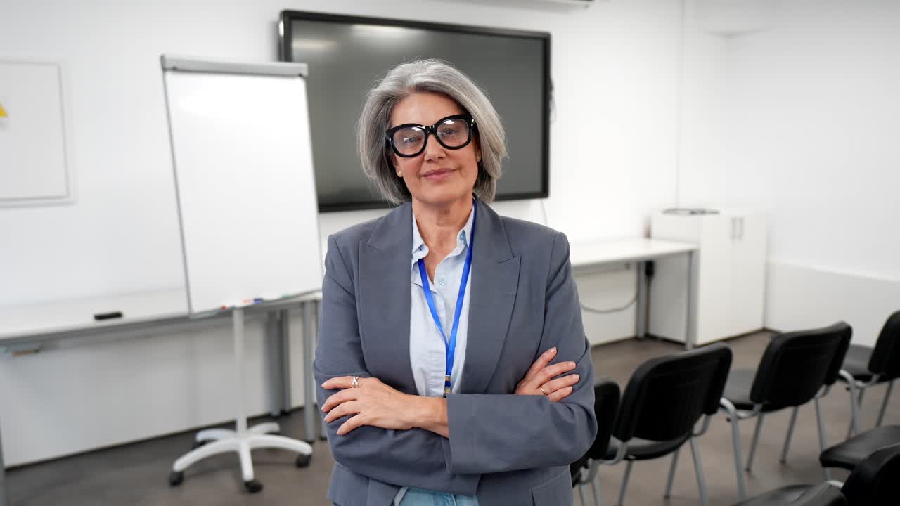 Selvsikker moden forretningskvinde smiler i et tomt konferencelokale.