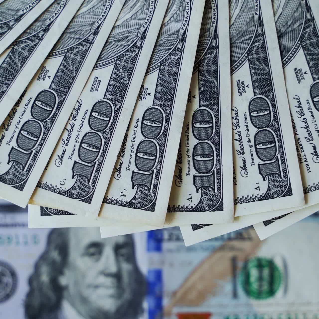 Rich background of dollars. Hundred banknotes rotating on the table. American money spinning. Cash. Close-up.