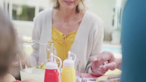 Happy-caucasian-family-having-dinner-and-praying-in-garden