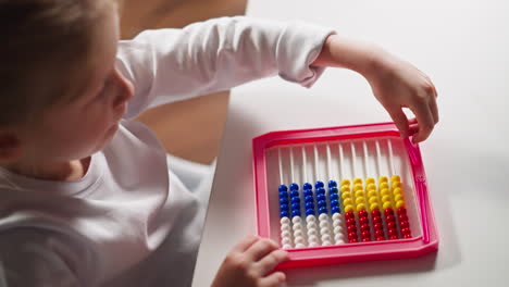 smart girl pours beads and puts stick to abacus at lesson