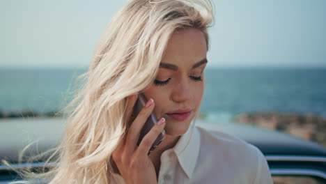 mujer triste llamando al teléfono de pie en la orilla del océano primer plano. niña hablando teléfono inteligente