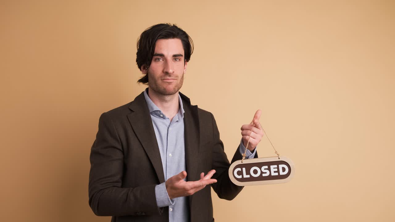 Upset businessman with closed sign in brown studio