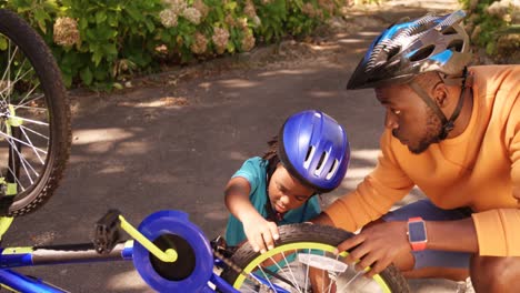 el padre está ayudando a su hijo a reparar la bicicleta
