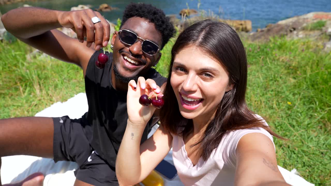Couple enjoying a picnic with cherries on the beach
