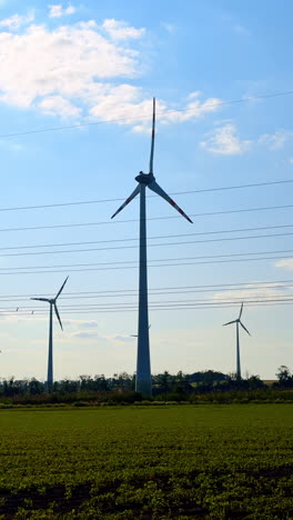 wind turbines produce green energy. wind turbines stand tall against a blue sky while producing clean energy in a rural setting with green fields