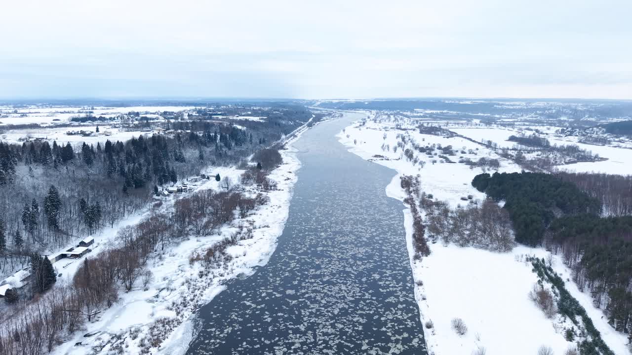 Droonivideo esittelee upean ilmakuvan mutkittelevasta joesta, joka halkoo maalauksellista lumista maisemaa. Tyyni talvimaisema on vangittu kauniisti terävällä ja kylmällä valaistuksella.