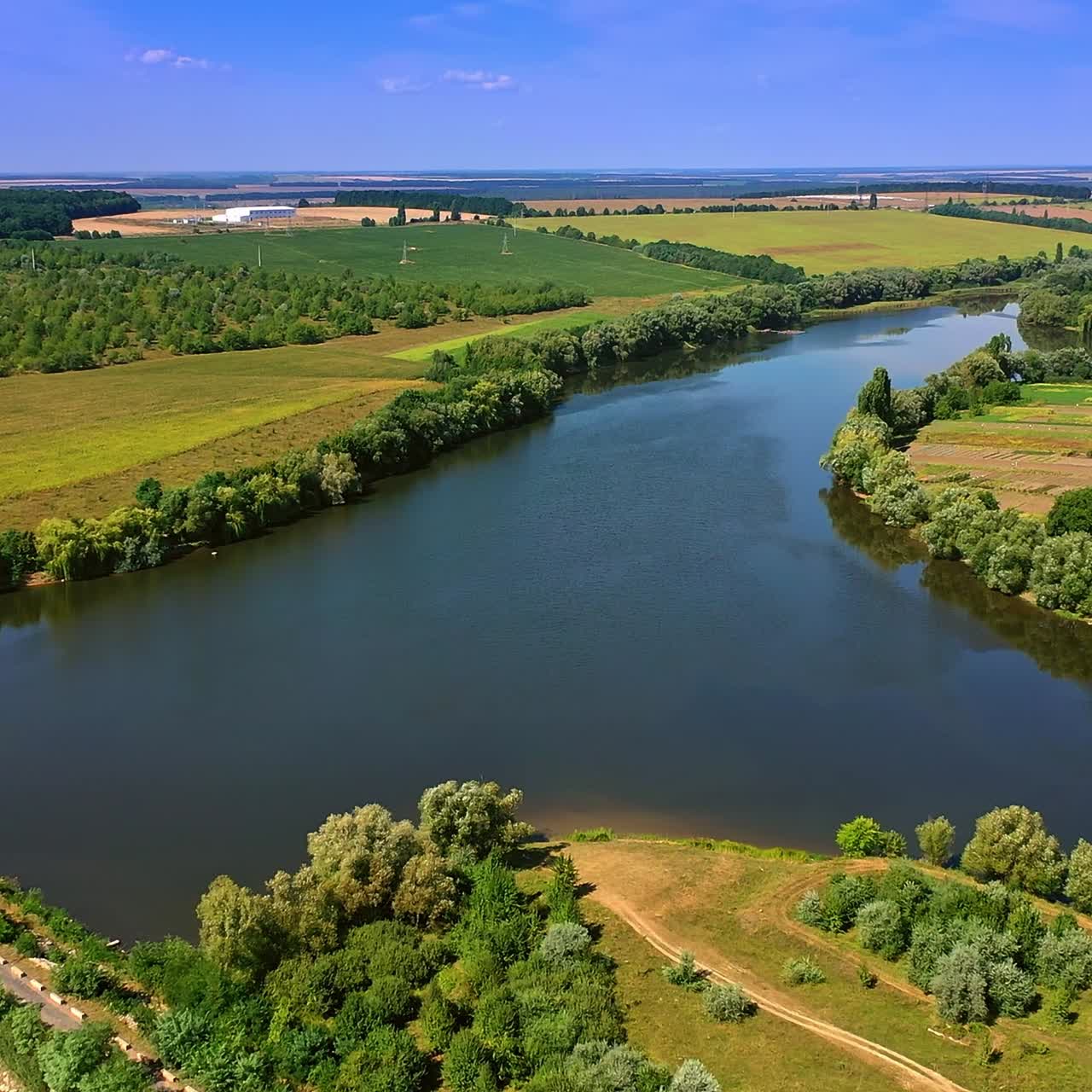 Lovely Ukrainian village on the picturesque river bank. Amazing nature of countryside on sunny summer day. Top view