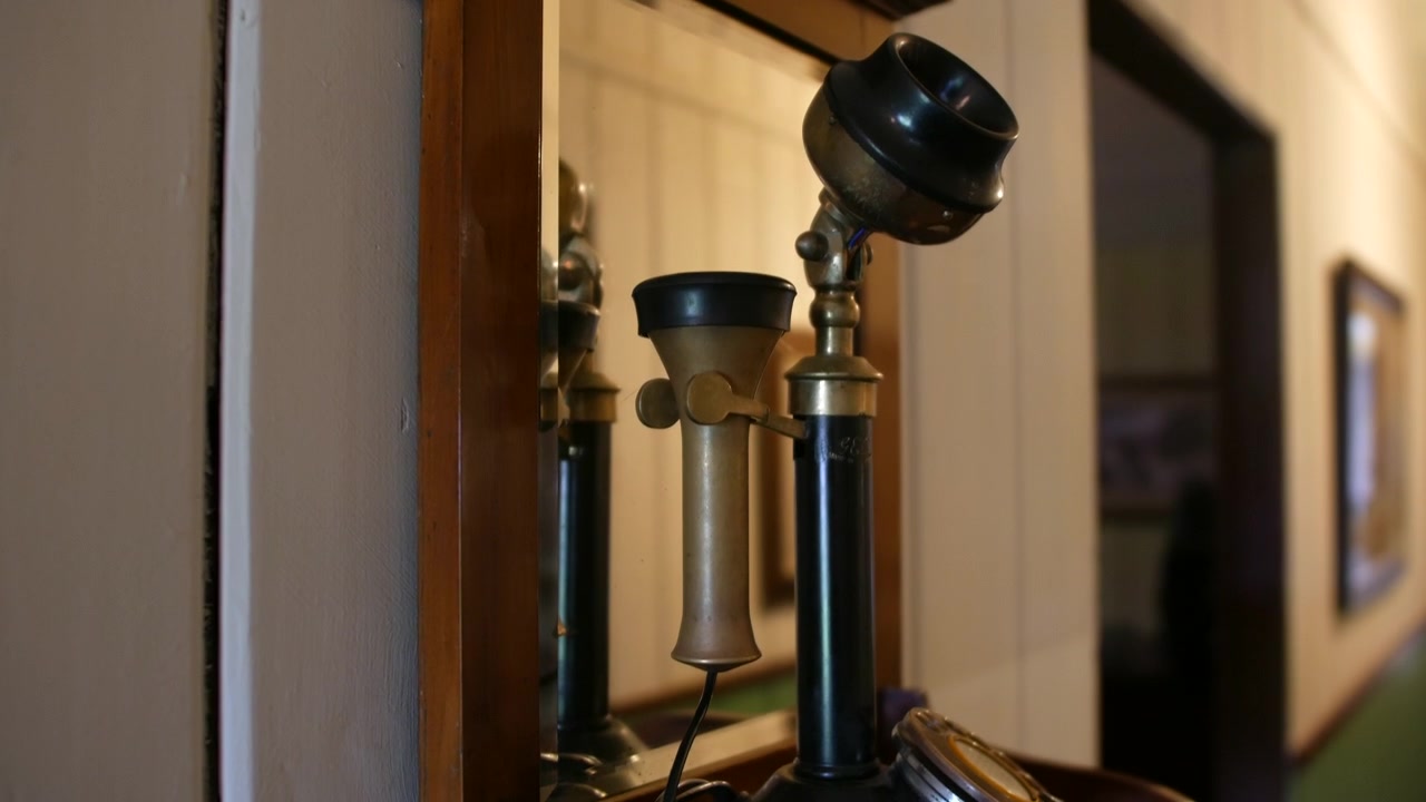 Un telefono a disco vintage e una cornetta su uno scaffale davanti a uno specchio