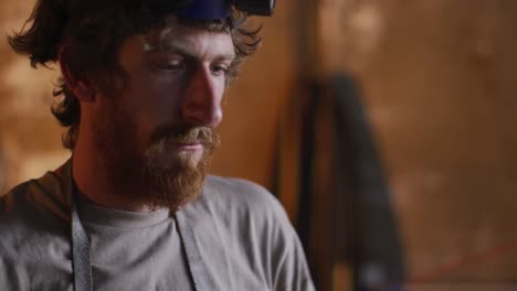 caucasian male blacksmith wearing breathing mask in workshop