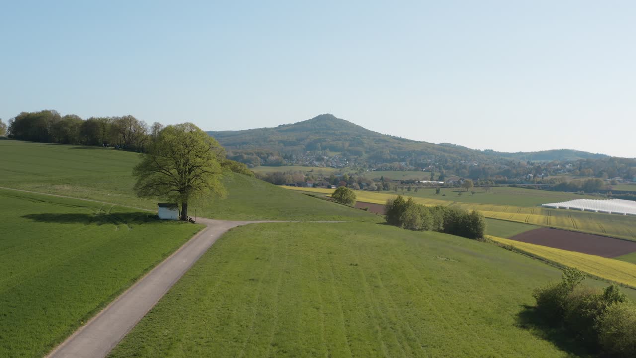 Drone - Aerial panorama shot of al lonely chapel on a field with grass and a road with panorama of the seven mountains - Siebengebirge 25p
