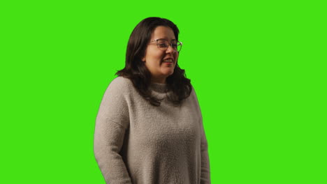 studio portrait shot of smiling casually dressed young woman wearing glasses standing against green screen background 2