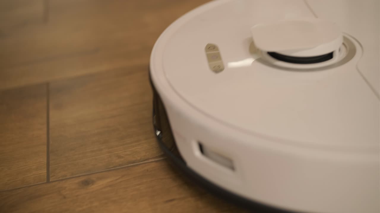 White Robotic Vacuum Cleaner Moving on Wooden Floor