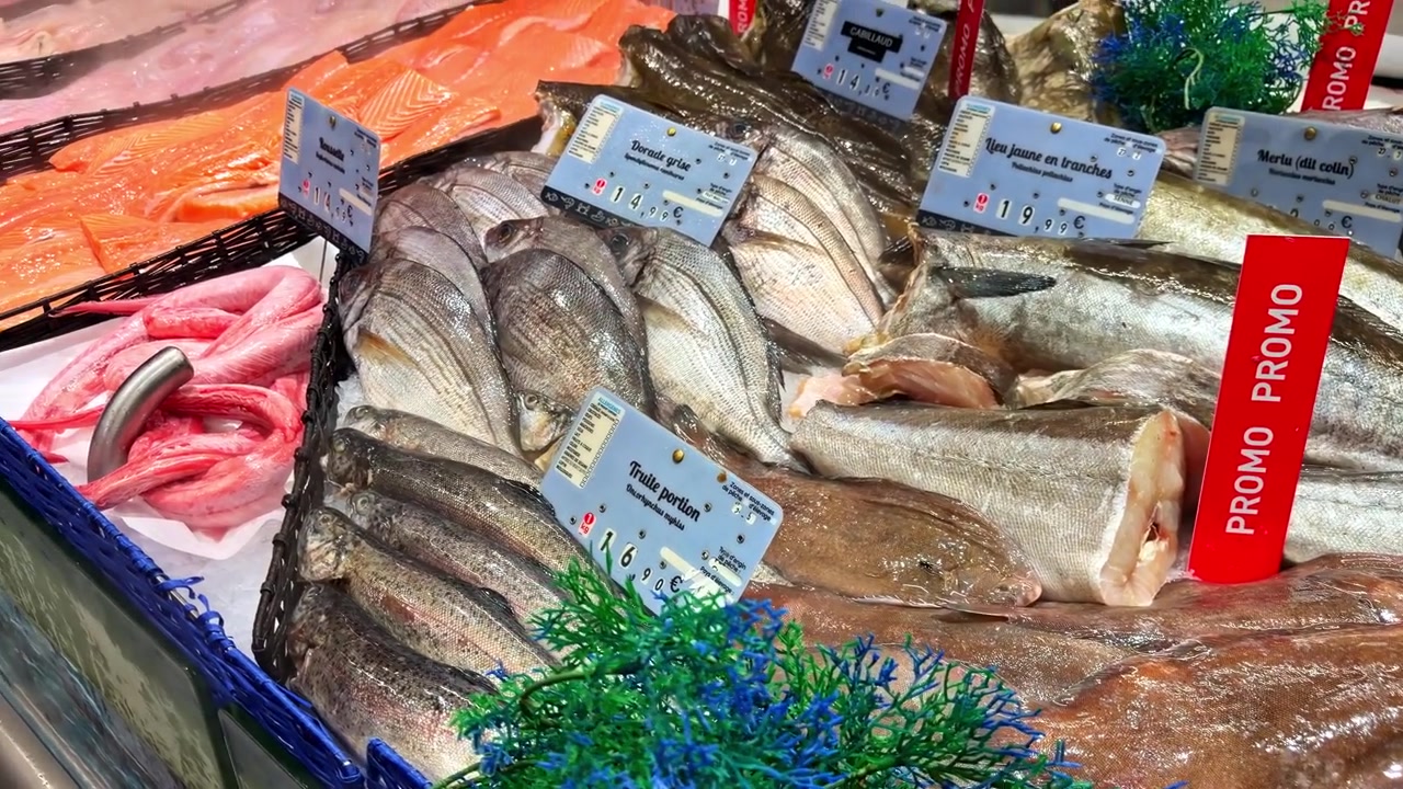 Pesce fresco esposto con cartelli in un affollato mercato del pesce di Cancale in Francia.