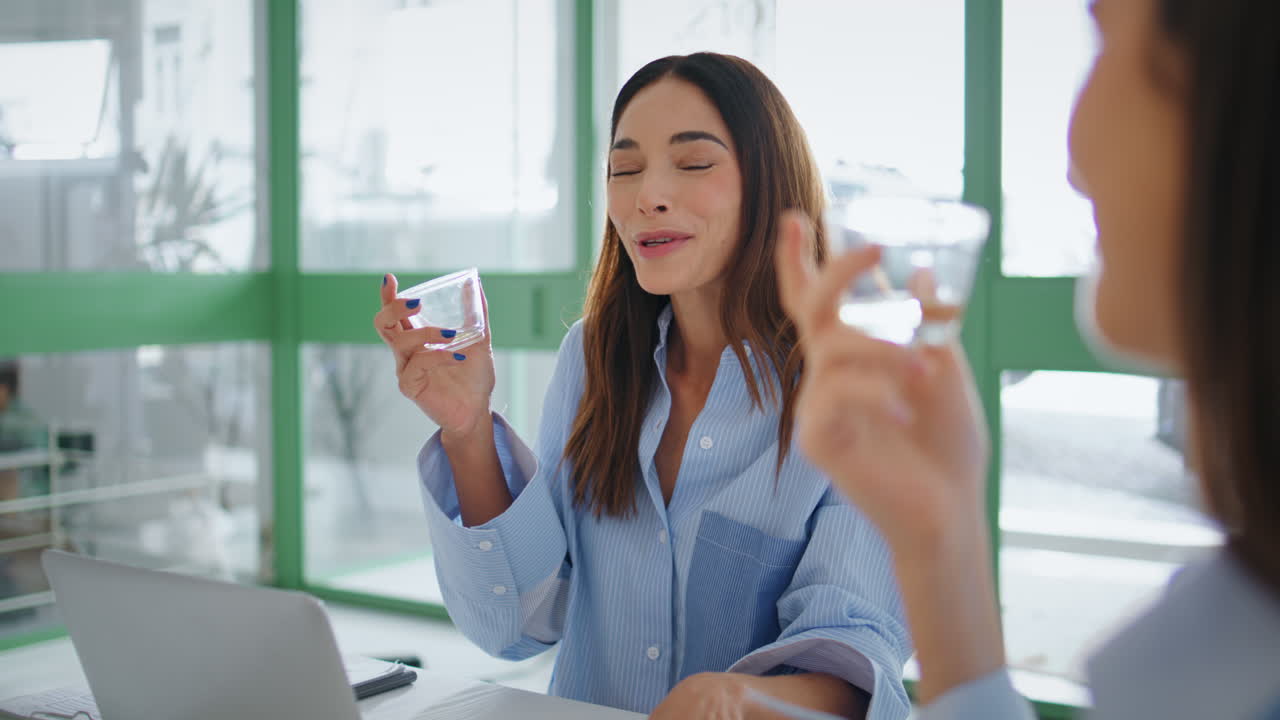 여성 경영자가 회의에서 물을 마시고 직원들이 회의에서 이야기합니다.