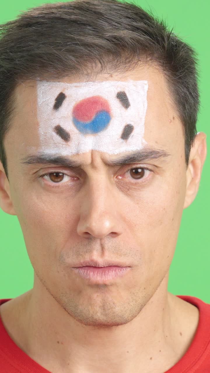 Serious man with a south korean flag painted on the face