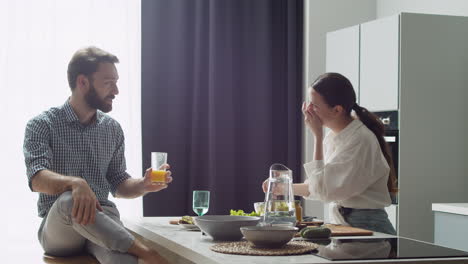 pareja alegre charlando y almorzando juntos en una cocina de estilo moderno