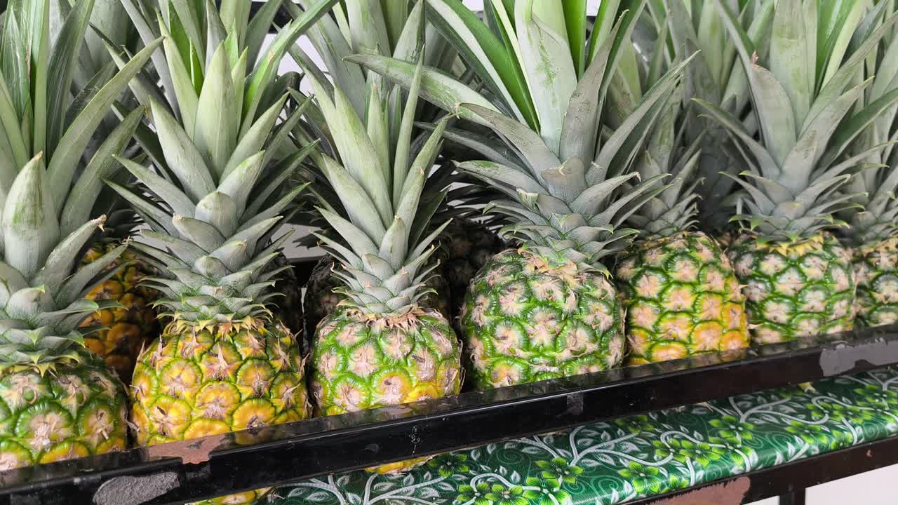 Ripe pineapples are neatly stacked and ready for market. These freshly harvested fruits are perfectly arranged for display. Their vibrant golden husks signal peak sweetness for buyers