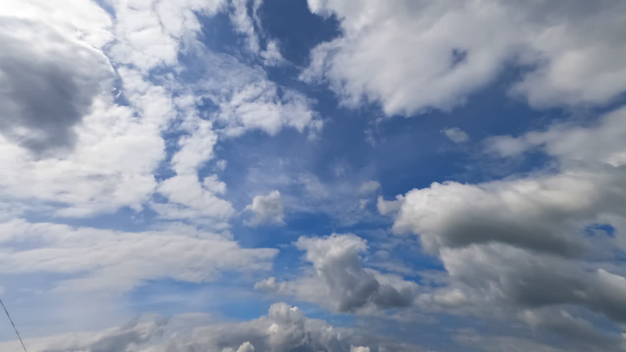 Flying among the clouds floating in the blue sky. Fluffy grey clouds changing shapes in atmosphere. Timelapse.