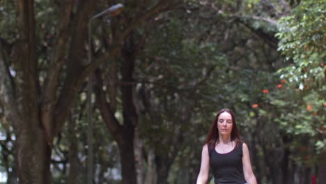 bajo la sombra de los árboles del parque una mujer joven caminando hacia una ubicación sentada