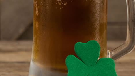 animation of clover leaf leaning on glass of beer in background