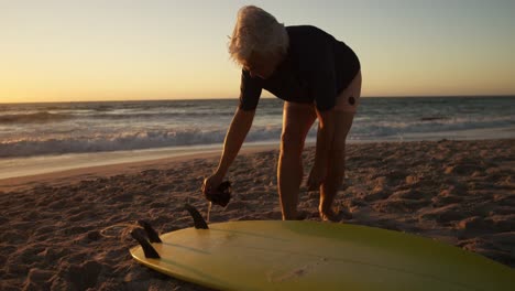 Ältere-Frau-Bereitet-Sich-Auf-Das-Surfen-Am-Strand-Vor